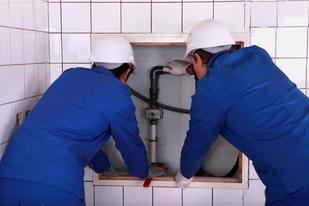 Two plumbers working on a pipe.