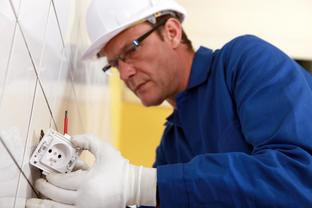 This is a picture of an electrician working on an outlet.